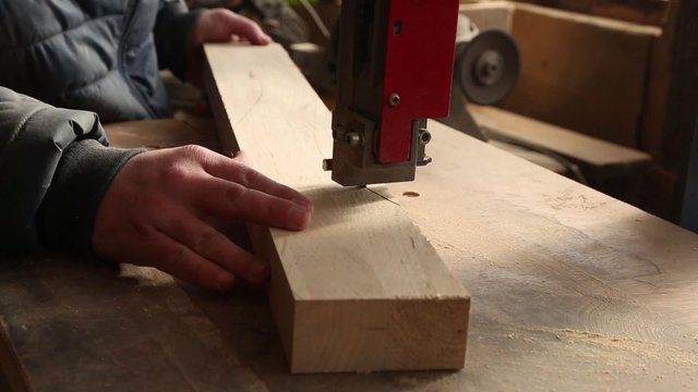 Joiner cuts piece of furniture in the woodworking machinery.