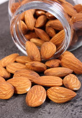 Almonds spilling out of glass jar on concrete structure