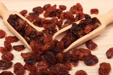 Brown raisins with spoon on wooden table, healthy eating