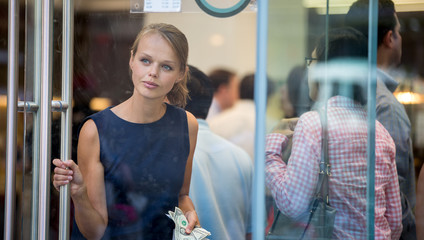 Pretty, young woman leaving a store/restaurant with cash