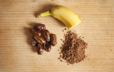 Zdrowe produkty, banan, daktyle kakao na drewnianej desce