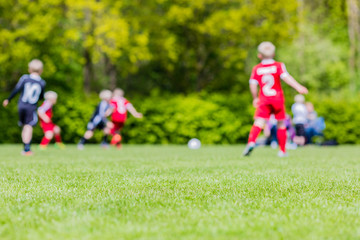 Obraz na płótnie Canvas Blurred kids playing youth football match