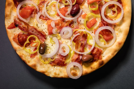 Delicious pizza with ham, vegetables and olives served on wooden