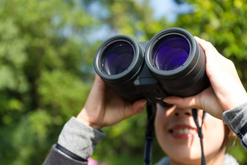 Woman looking though binoculars at forest