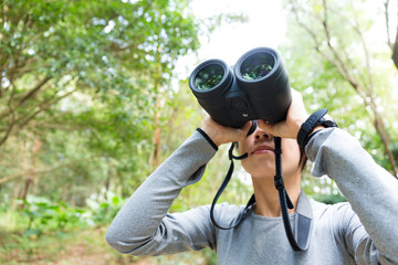 Young woman use of the binoculars and looking up