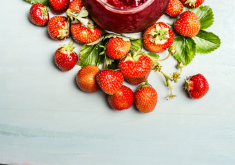 Strawberries preserve with fresh berries and jam-jar on  light wooden background, top view