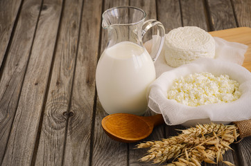 Fresh dairy products. Milk and cottage cheese with wheat on the rustic wooden background. Horizontal permission. Selective focus.