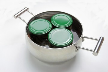 Steel pot with three jars boiling in the water. Isolated on white background