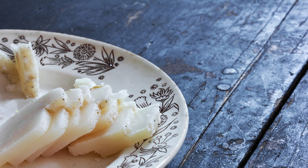 Salted pork fat cut into small pieces on a ceramic plate on an old black wooden table. Rustic...