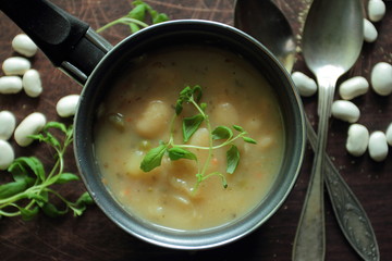 Fresh marjoram herbs in a small pot with bean soup
