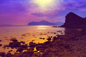 Purple sunset over rocky beach