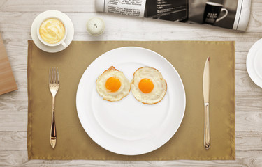Breakfast plate face. Eggs, plate, tablecloth, coffee, newspaper on table with a top view. 
