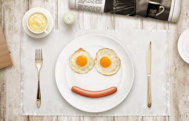 Breakfast smiling face. Eggs, hot dog, plate, tablecloth, coffee, newspaper on table with a top view. 