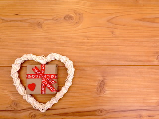 Weiße Herz mit Geschenk  auf Holzhintergrund