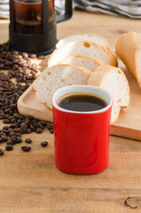 Americano in red cup with coffee beans on wooden background