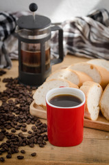 Americano in red cup with coffee beans on wooden background