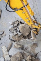 Yellow excavator carries dirt in a bucket.