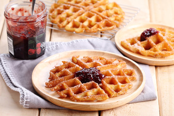 waffles with raspberry jelly on wooden background.