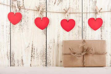 Gift box with heart-shaped tags on wooden background