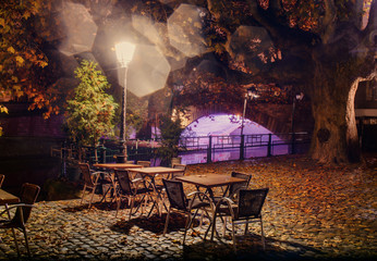 Fototapeta na wymiar Empty tables under a lamp at night in the fog on the city waterfront
