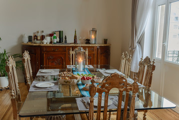 Beautiful glass table with food and antique chairs in a room with a window