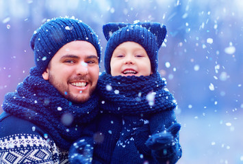 happy father and son having fun under winter snow, holiday season