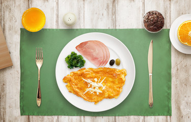 Served breakfast. Omelet, ham, salad, olive on plate. Top view.