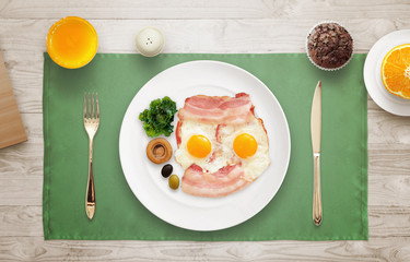 Breakfast served. Eggs, bacon, mushroom, salad, olive on a plate.