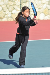 Fototapeta na wymiar Young girl playing tennis on a court