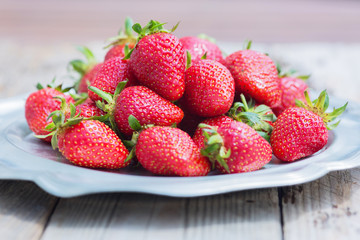 Fresh and delicious organic strawberries on old metal plate, on wooden table. Perfect for your healthy eating and dieting. Selective focus. Natural sunlight.