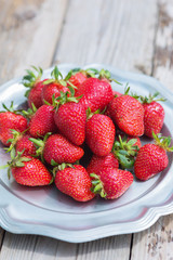 Fresh and delicious organic strawberries on old metal plate, on wooden table. Perfect for your healthy eating and dieting. Selective focus. Natural sunlight.