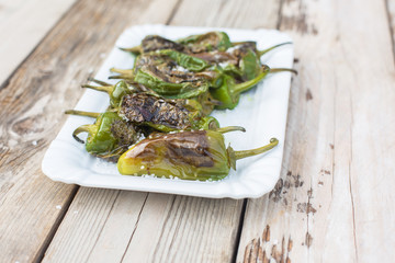 Pimientos de Padrón with sea salt in white bowl on wooden table - light and delicious spanish snack
