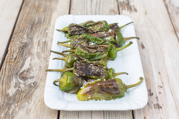 Pimientos de Padrón with sea salt in white bowl on wooden table - light and delicious spanish snack
