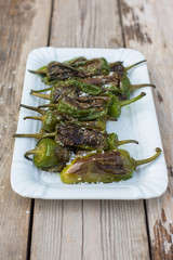 Pimientos de Padrón with sea salt in white bowl on wooden table - light and delicious spanish snack
