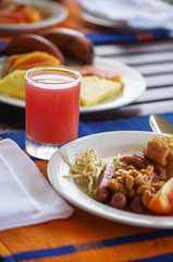 Breakfast scene with fresh glass of juice, tropical fruits and vegetables