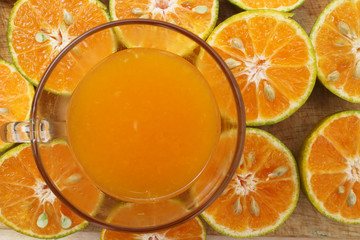 glass of fresh orange juice and oranges on a vintage wooden background