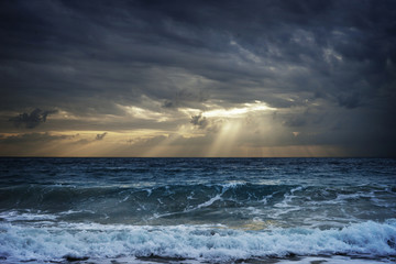 Dark clouds over stormy sea hiding sunlight in Thailand.