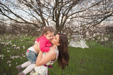 Fototapeta premium Mom kisses and hugs daughter on nature, family, motherhood, child