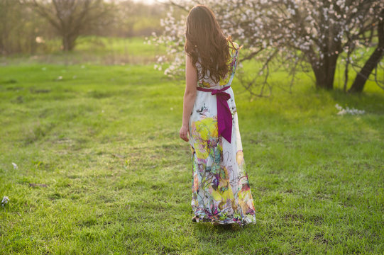 Girl with beautiful hair standing back in the lush spring garden, beauty, makeup, hair,