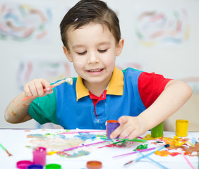 Little boy is playing with paints