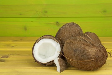 Cracked coconut on yellow wooden table. Preparing coconut refreshing drink. Tropical drink. The table at the beach bar. A refreshing drink made from coconut milk.
