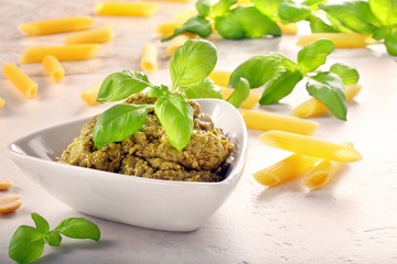 Green basil pesto in white bowl