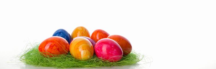 Bunt gefärbte Ostereier in grünem Grasnest vor hellem Hintergrund