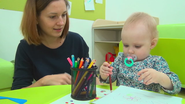 Mother and little baby plays with pencils