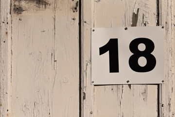 Hausnummer 18 in schwarzen Ziffern auf einer alten Bretterwand