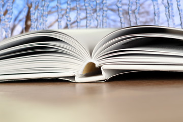 Fototapeta premium Open book on a wood table over blue winter light background