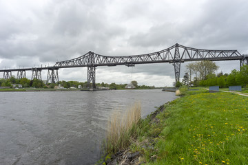 Fototapeta premium Hanging ferry and Rendsburg High Bridge railway viaduct over the Kiel Canal at Rendsburg in the German state of Schleswig-Holstein.
