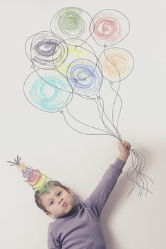 Child with balloons. The painting on the wall. Postcard happy birthday. Imagination, celebration and freedom concept.