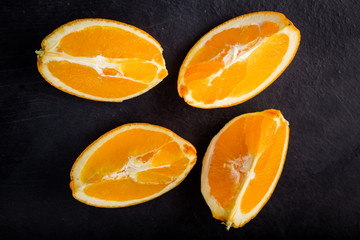 Orange slices on black wooden background