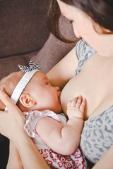 Breastfeeding. Mother feeding her baby girl at home